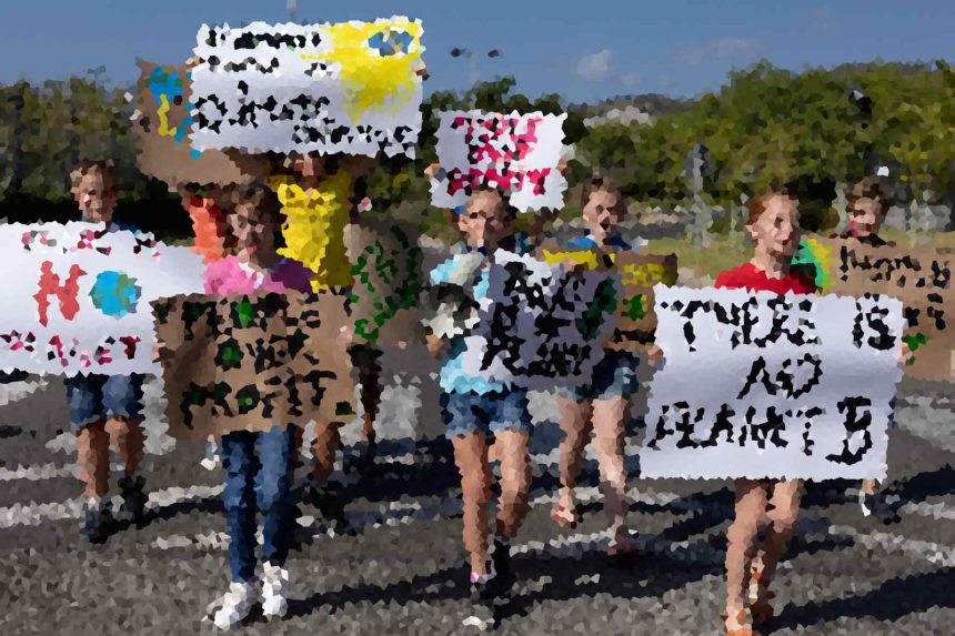 Group of people holding protest signs at an outdoor event on a sunny day, marching together.