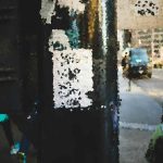 Abstract, pixelated urban street scene suggesting storefronts and pedestrians with colorful lights and dark shadows.