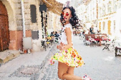 Young woman in a bright yellow floral dress walking down a sunlit city street with buildings on both sides.