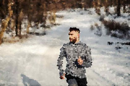 Man running along a snowy forest path in a gray jacket, blurred by pixelation, winter scene