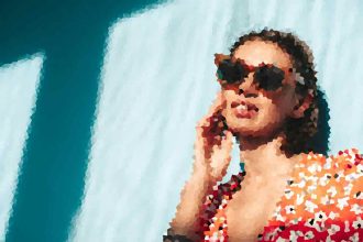 Person wearing a red floral shirt and sunglasses, talking on a cellphone against a blue background.