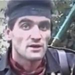 Man wearing a dark headband and jacket outdoors near a green metal staircase.