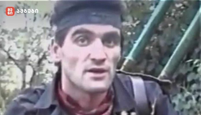 Man wearing a dark headband and jacket outdoors near a green metal staircase.