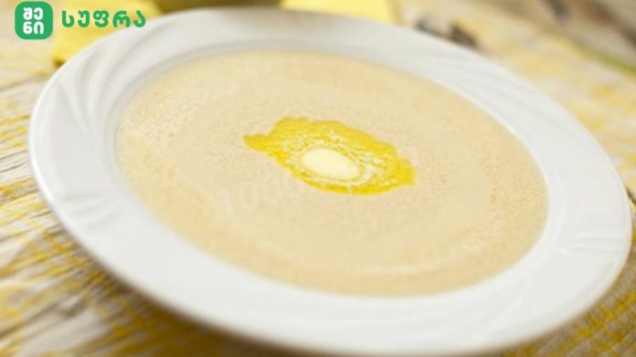 Creamy soup in a white bowl on a plate, with a small butter pat in the center.