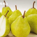 Assortment of green pears on a light wooden surface, one pear cut open to show white flesh and seeds, with a logo in the top-left corner.