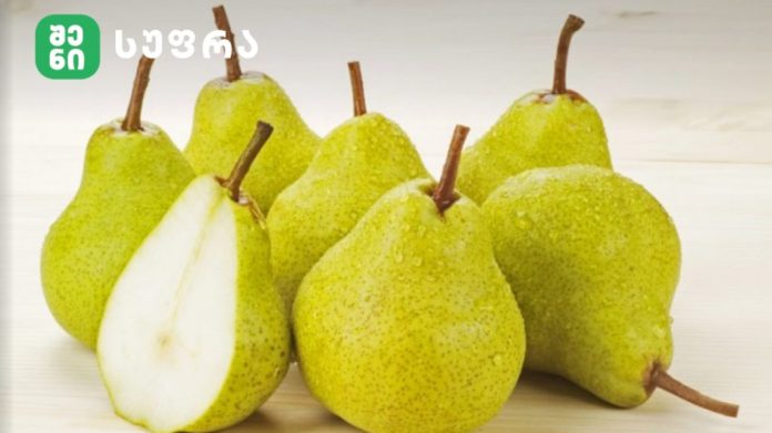 Assortment of green pears on a light wooden surface, one pear cut open to show white flesh and seeds, with a logo in the top-left corner.