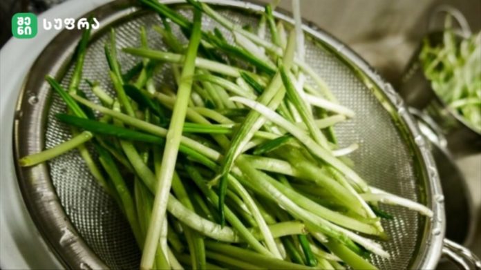 Green onions (scallions) sliced into thin spears in a metal colander, ready to rinse/or drain.