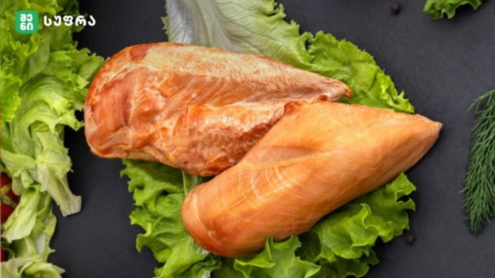 Two raw salmon fillets resting on a bed of lettuce on a dark surface.