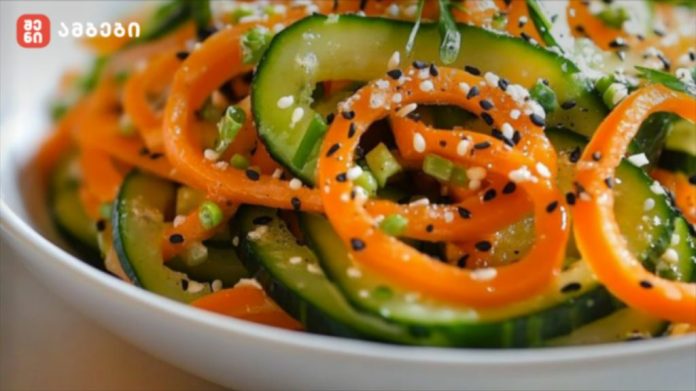 Close-up of a cucumber and carrot salad in a white bowl, topped with white and black sesame seeds.