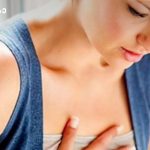 Woman performing a breast self-exam, pressing her chest with fingers