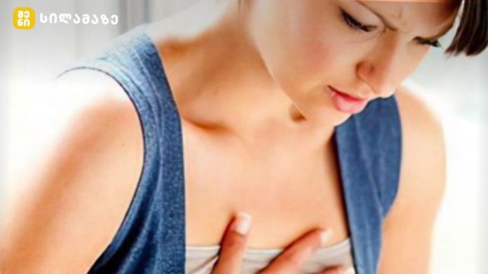 Woman performing a breast self-exam, pressing her chest with fingers