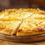 Cheese pizza on a round wooden board, sliced into eight pieces.