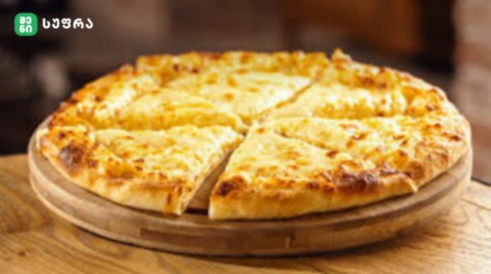 Cheese pizza on a round wooden board, sliced into eight pieces.