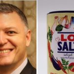 Smiling man in a suit on the left, and a colorful LO SALT iodized salt can labeled GMO free on the right.