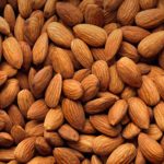 Close-up of almonds piled together, with a small green brand logo in the top-left corner.