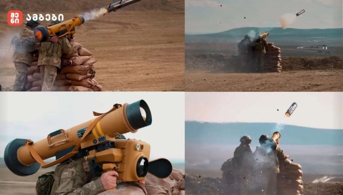 Soldiers in camouflage firing a yellow rocket launcher from behind sandbags at a military training range.