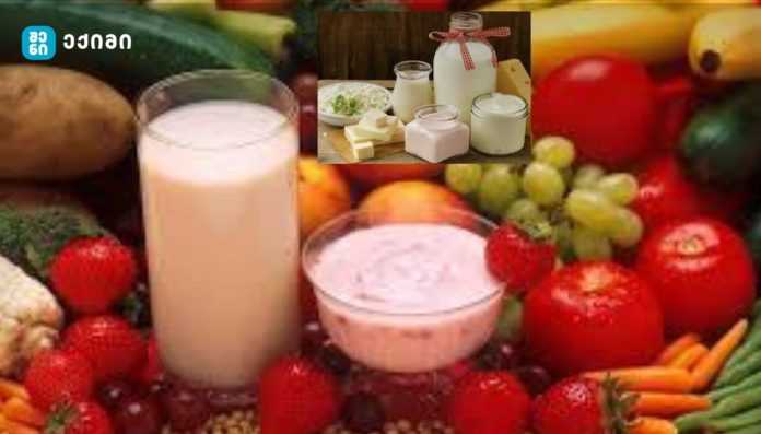 Collage of fresh produce with a central milk bottle and a bowl of yogurt; inset shows jars of milk, yogurt, and butter with a red ribbon, over a background of fruits and vegetables. Brand logo with Georgian text in the top-left corner.
