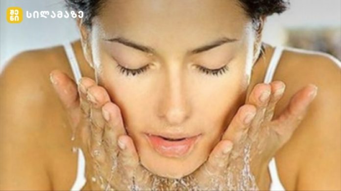 Close-up of a woman rinsing her face with water, cupping water on her cheeks during a skincare routine