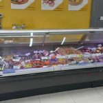 Glass-front deli case filled with assorted sausages and meats on display in a store setting