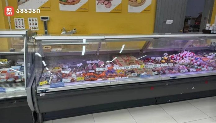 Glass-front deli case filled with assorted sausages and meats on display in a store setting