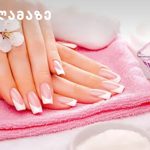 Hands with a pink French manicure resting on a folded pink towel at a spa