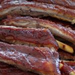Close-up of glossy, barbecued pork ribs stacked on top of each other.