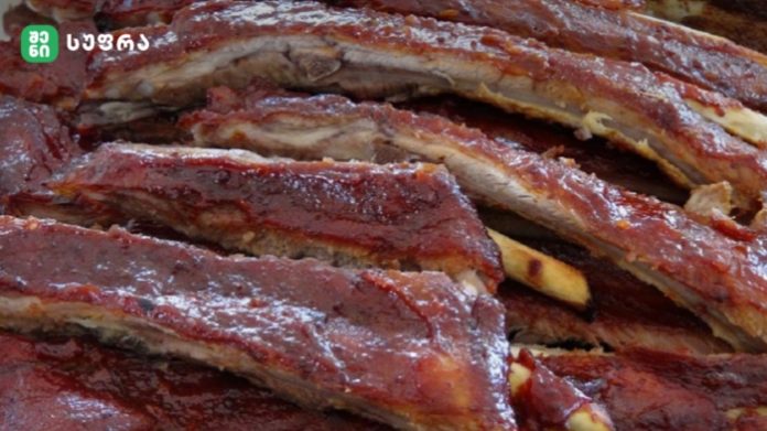 Close-up of glossy, barbecued pork ribs stacked on top of each other.