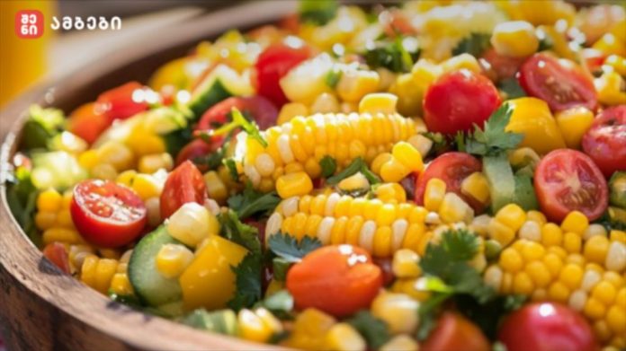 Colorful corn salad with cherry tomatoes, cucumber, yellow peppers and fresh herbs in a wooden bowl.