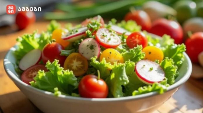 Bowl of fresh garden salad with lettuce, cherry tomatoes, radish slices, and yellow tomatoes on a wooden table, with a logo in the top-left corner.