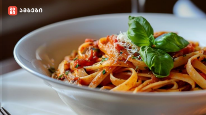 Bowl of spaghetti with tomato sauce, grated cheese, and fresh basil on a white plate.
