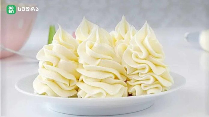 Plate of white buttercream rosettes piped in decorative swirls on a plate
