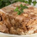 Pile of shredded roasted meat on a white plate, topped with a sprig of parsley.