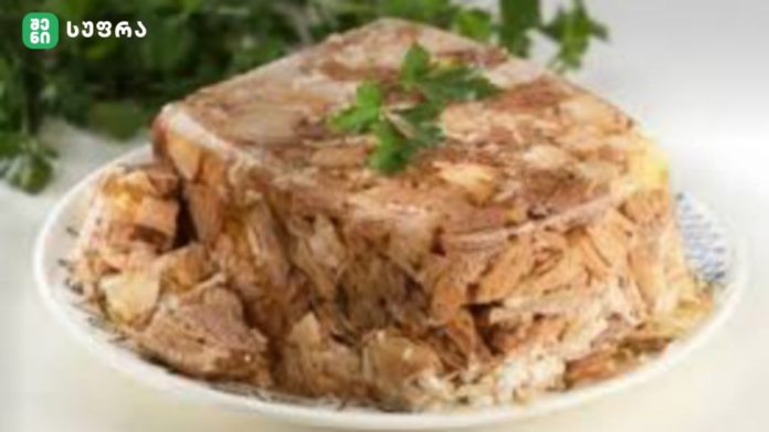 Pile of shredded roasted meat on a white plate, topped with a sprig of parsley.