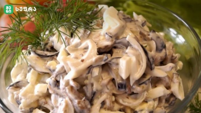 Creamy mushroom and cheese pasta salad in a clear glass bowl, topped with a dill sprig.