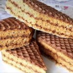 Stack of chocolate wafer cookies on a white plate, with layered filling and a ridged surface.