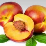 Three ripe peaches, one cut open to reveal the pit, with green leaves on a white gradient background.
