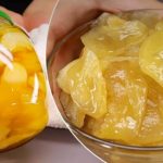 Glass jar filled with sliced yellow peaches in syrup beside a bowl of peach slices on a fork.