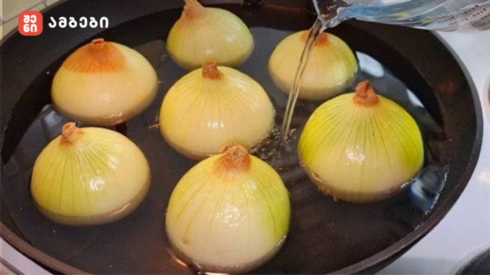 Onions boiling in a pot of water on a stove, their yellowish skins visible above the liquid level.