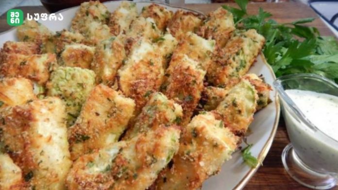 Plate of golden-brown breaded fried pieces with herbs, served with a creamy dipping sauce on the side and parsley garnish.