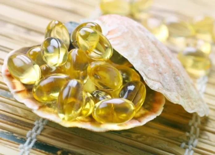 Seashell filled with yellow softgel capsules on a woven mat, suggesting fish oil capsules.