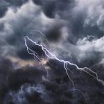 Lightning bolt arcs through dark storm clouds as rain falls across the scene.