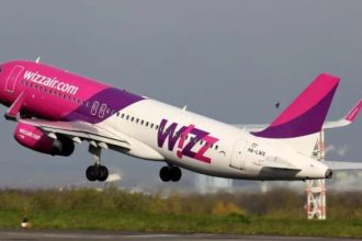 Wizz Air jet taking off from the runway with pink and purple livery in ascent.