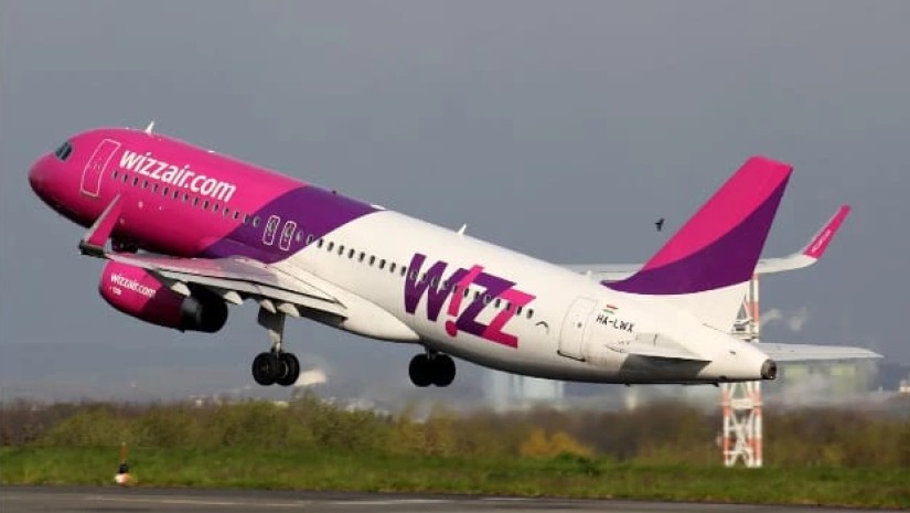 Wizz Air jet taking off from the runway with pink and purple livery in ascent.