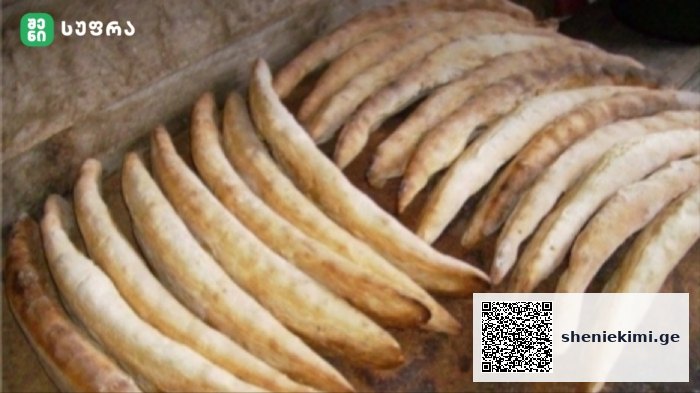 Row of curved breadsticks cooling on a baking tray, lightly browned and crusty.