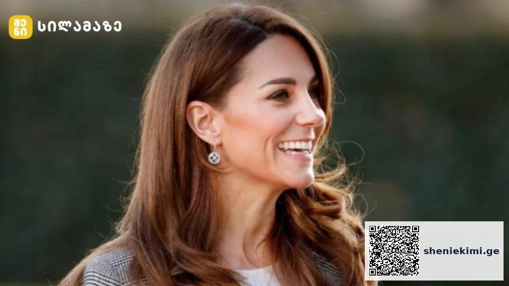 Smiling woman with long brown hair outdoors, wearing earrings, facing right side of frame with a blurred natural background.
