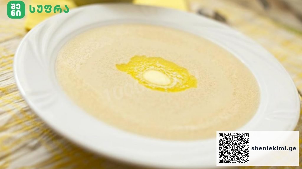 Creamy soup in a white bowl on a plate, with a small butter pat in the center.