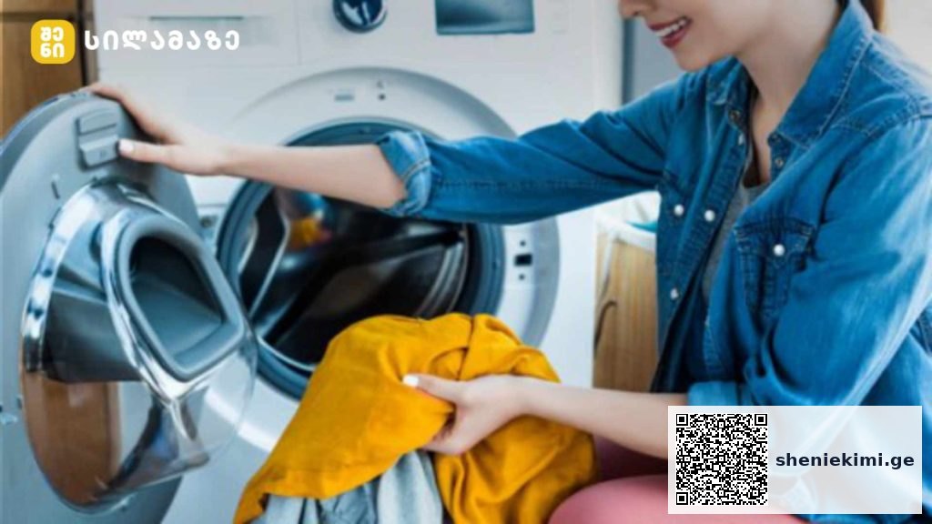 Young woman loading orange clothing into a front-loading washing machine in a laundry room.