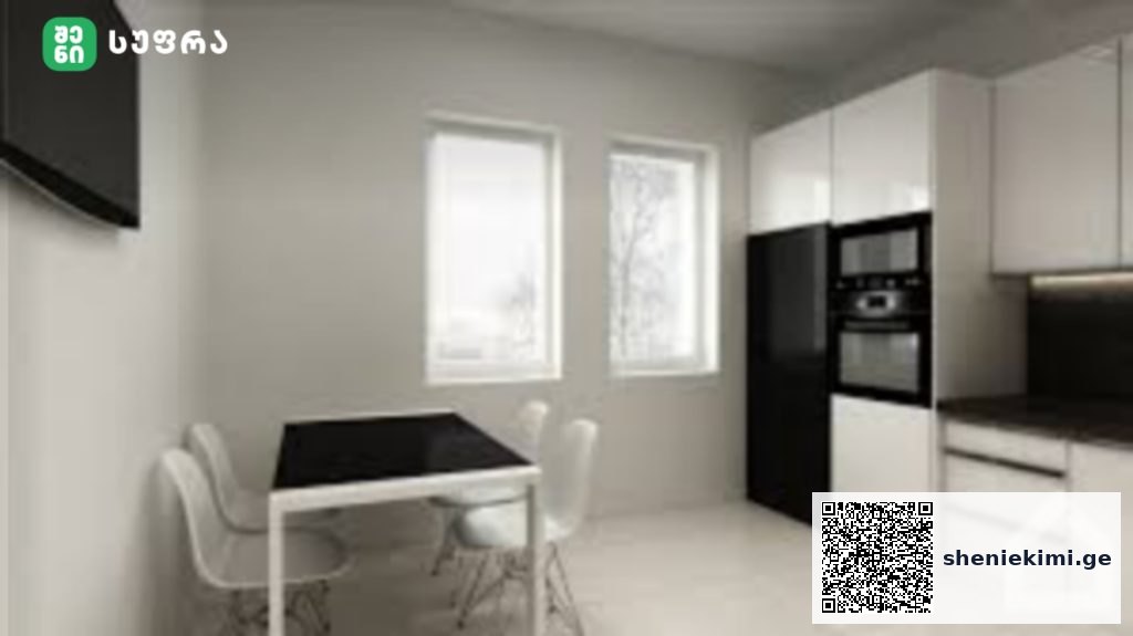 Modern white kitchen with black dining table and four white chairs, built-in oven, and two windows.