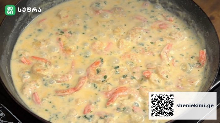 Creamy yellow sauce with diced chicken, red peppers and herbs simmering in a skillet.