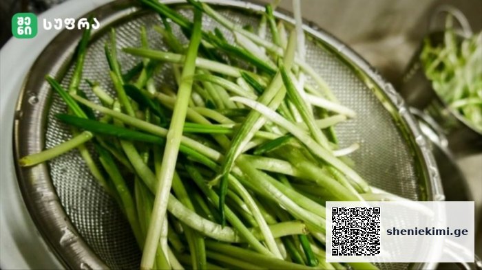 Green onions (scallions) sliced into thin spears in a metal colander, ready to rinse/or drain.